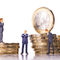 Modellfiguren von Geschäftsleuten mit Euromünzen.
