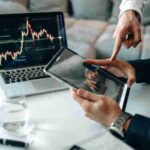 Business professionals analyzing stock market data on tablet and laptop indoors., tags: top-langlebigkeits-investments 2025: chancen - pexel
